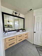 Bathroom with vanity, a textured ceiling, and light tile patterned floors