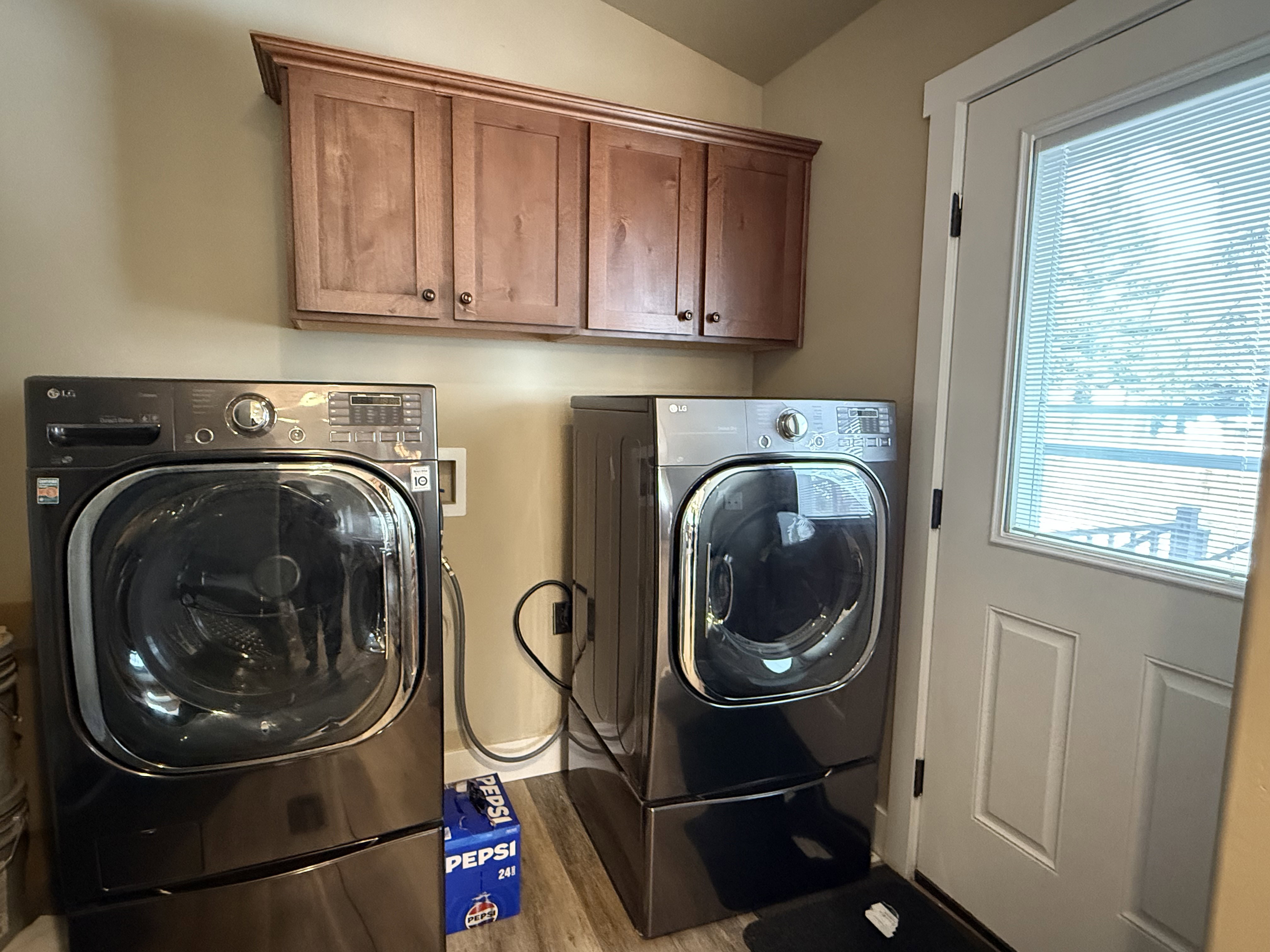 Laundry room featuring independent washer and dryer, cabinet space, lofted ceiling, and light wood-type flooring