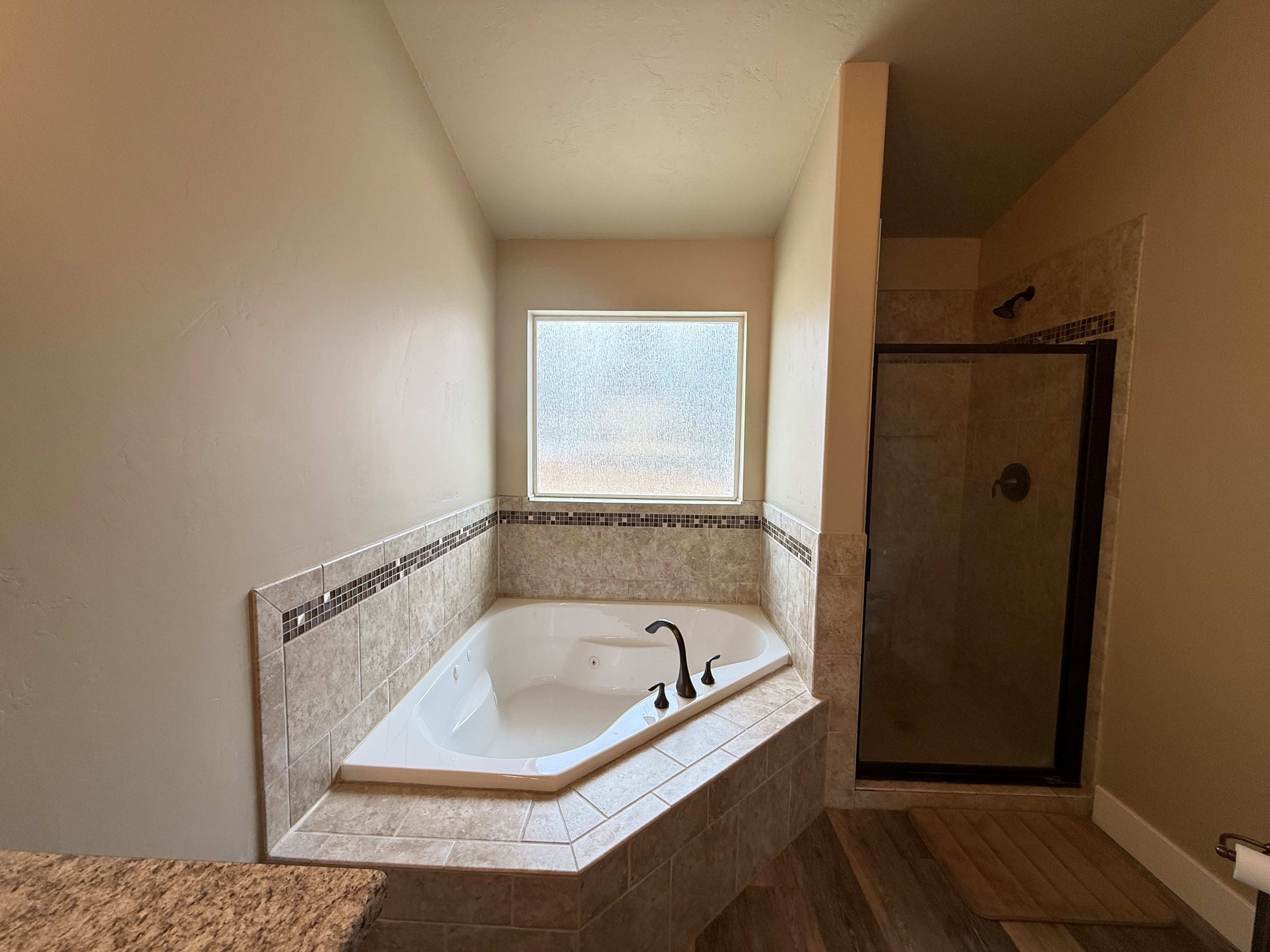 Bathroom featuring a tub with jets, a shower stall, and wood finished floors