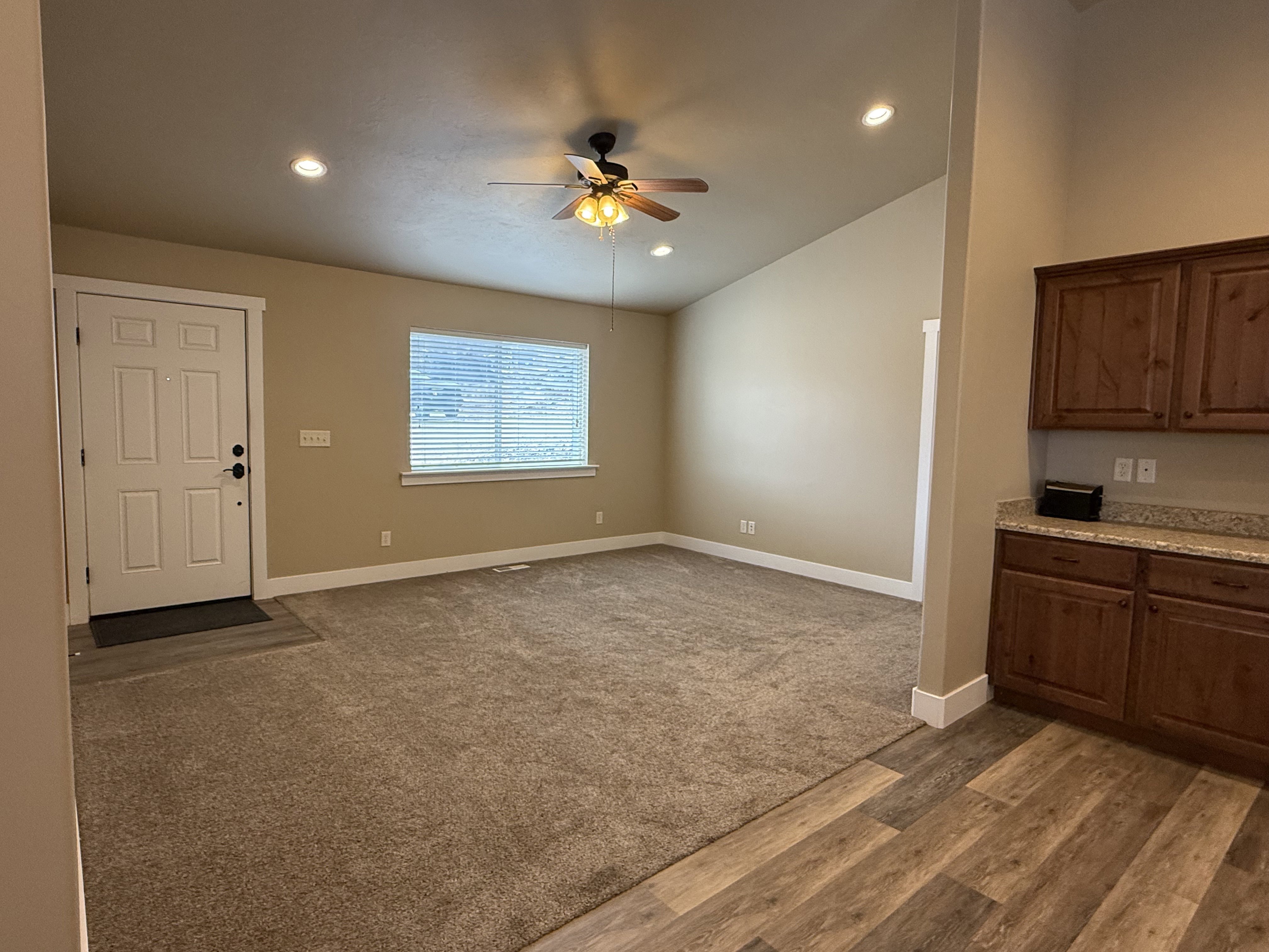 Unfurnished living room featuring a ceiling fan, vaulted ceiling, dark wood-style floors, dark colored carpet, and recessed lighting