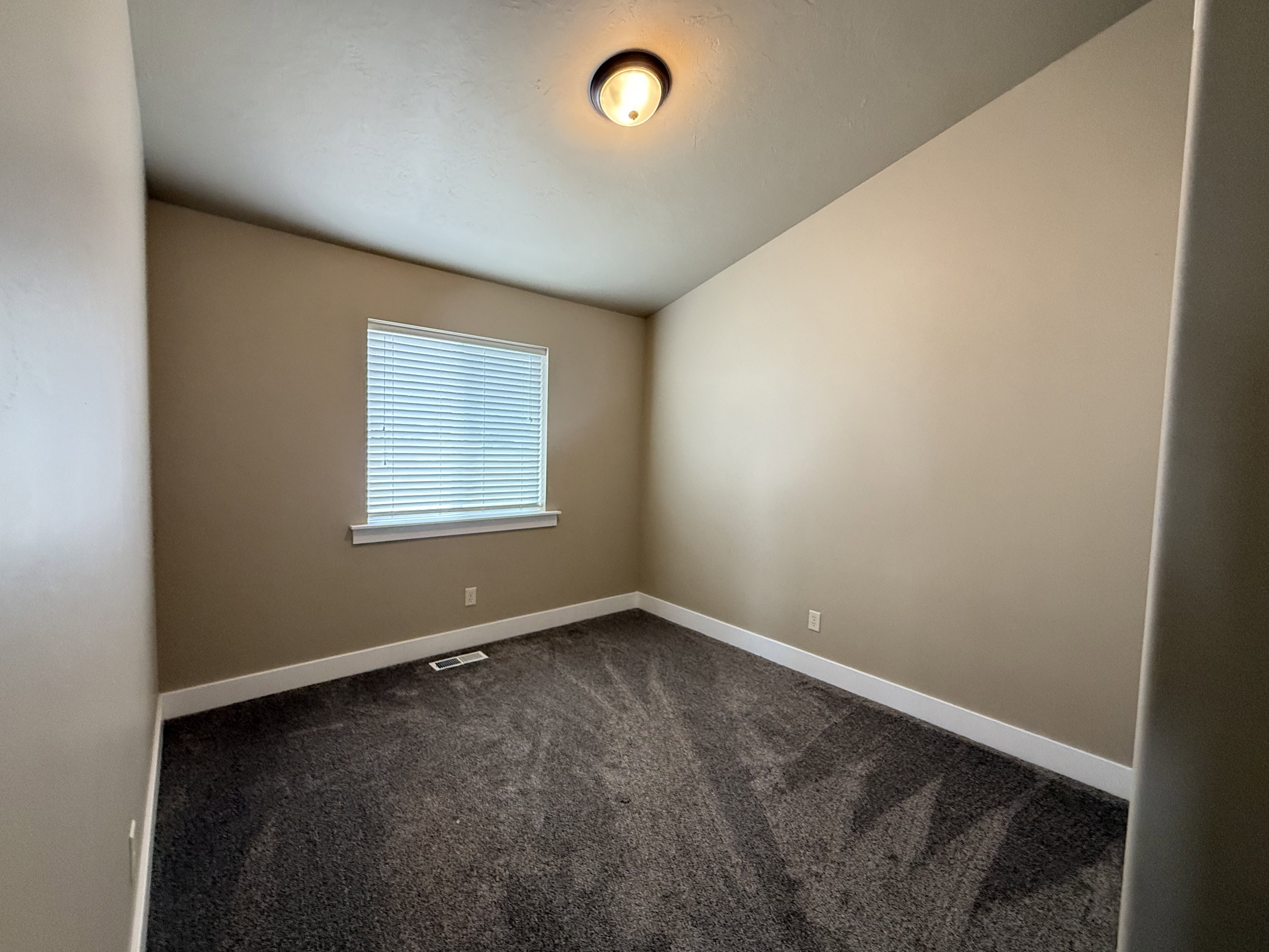 Spare room with dark colored carpet and vaulted ceiling