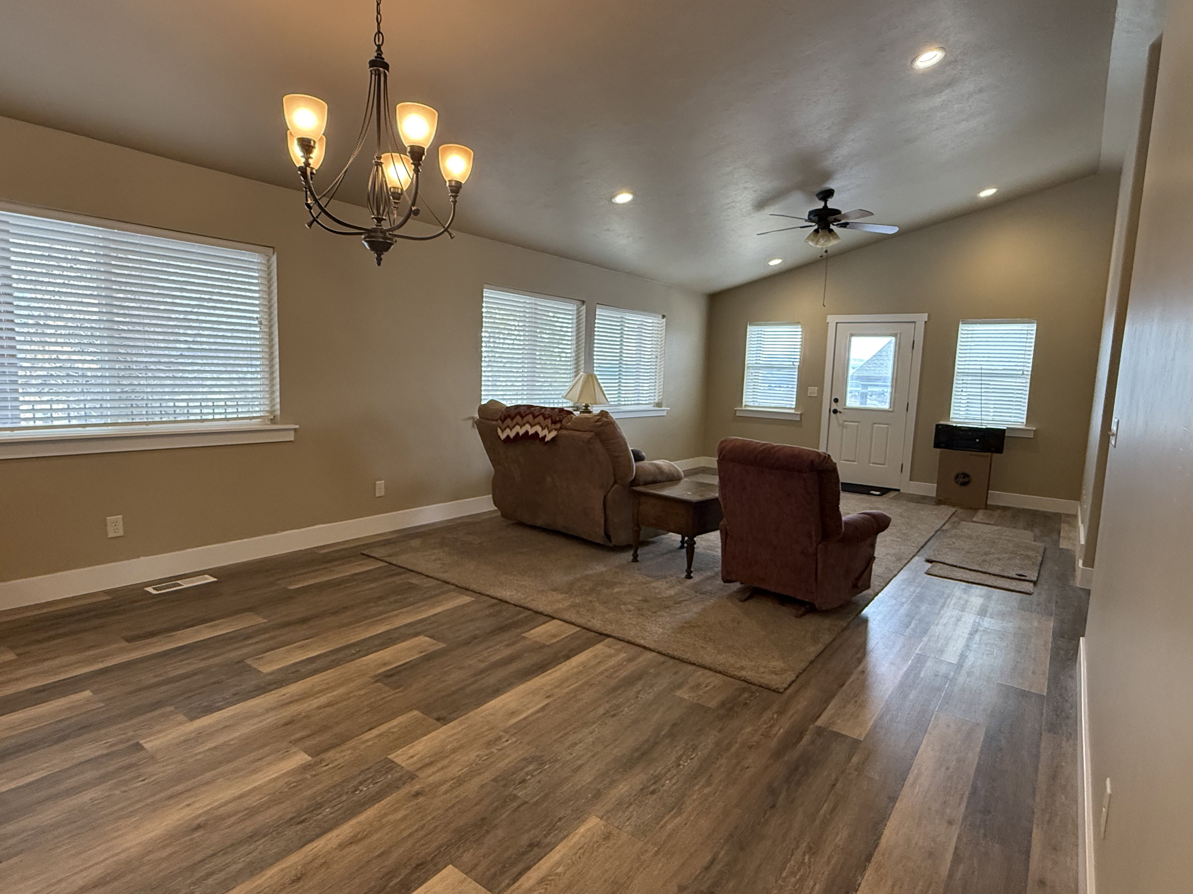 Living area with dark wood finished floors, plenty of natural light, hanging lights, lofted ceiling, and a ceiling fan