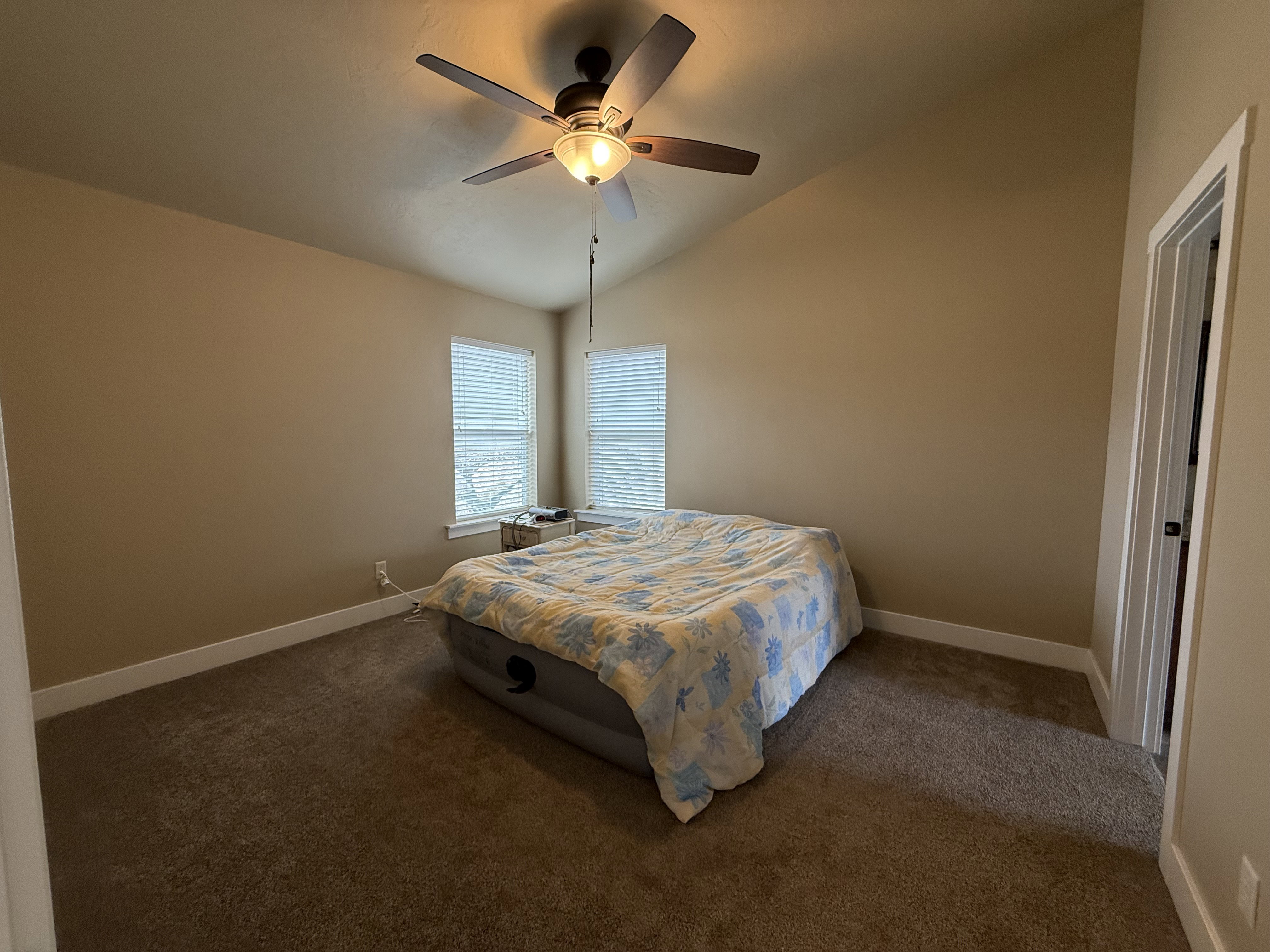 Carpeted bedroom featuring vaulted ceiling and a ceiling fan