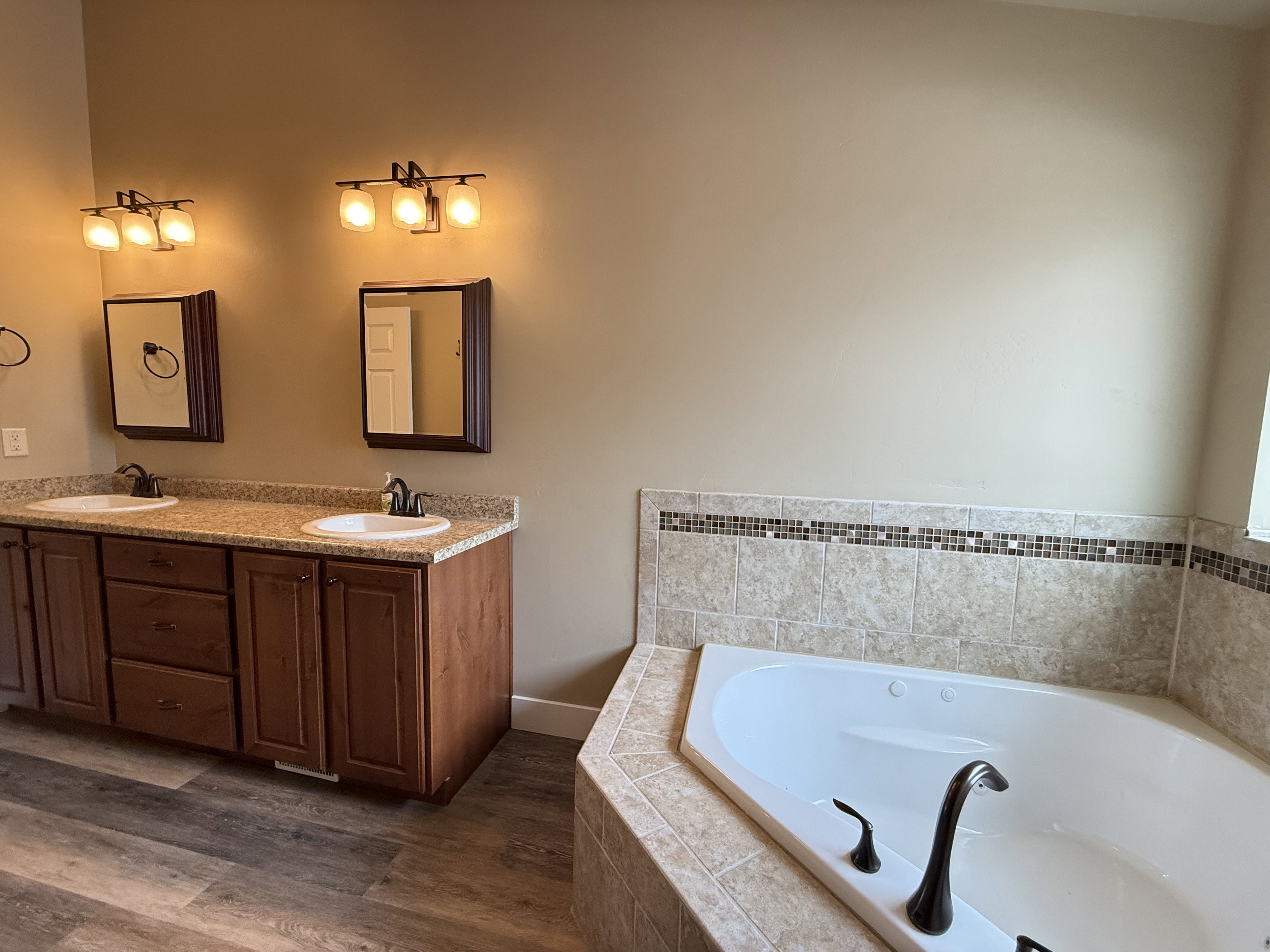Bathroom featuring double vanity, a bath, and dark wood finished floors