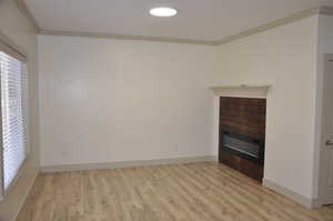 Unfurnished living room with crown molding, light wood finished floors, and recessed lighting