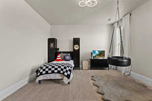 Carpeted bedroom featuring baseboards and a textured ceiling