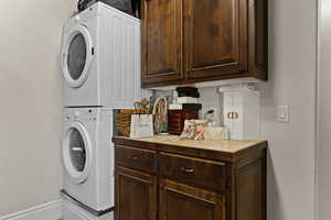 Laundry area featuring stacked washer / dryer and cabinet space