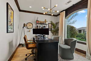 Home office featuring suspended lighting, ornamental molding, and light wood finished floors