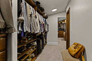Walk in closet featuring light carpet and vaulted ceiling