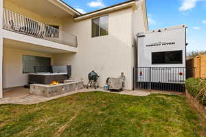 Rear view of house with a balcony, a patio area, stucco siding, and an outdoor fire pit