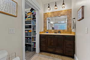 Bathroom featuring vanity, backsplash, a walk in closet, a shower with curtain, and light tile patterned floors