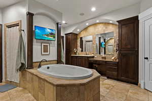 Bathroom with vanity, a bath, vaulted ceiling, and recessed lighting