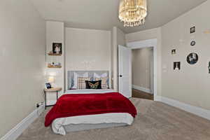Carpeted bedroom featuring suspended lighting and baseboards