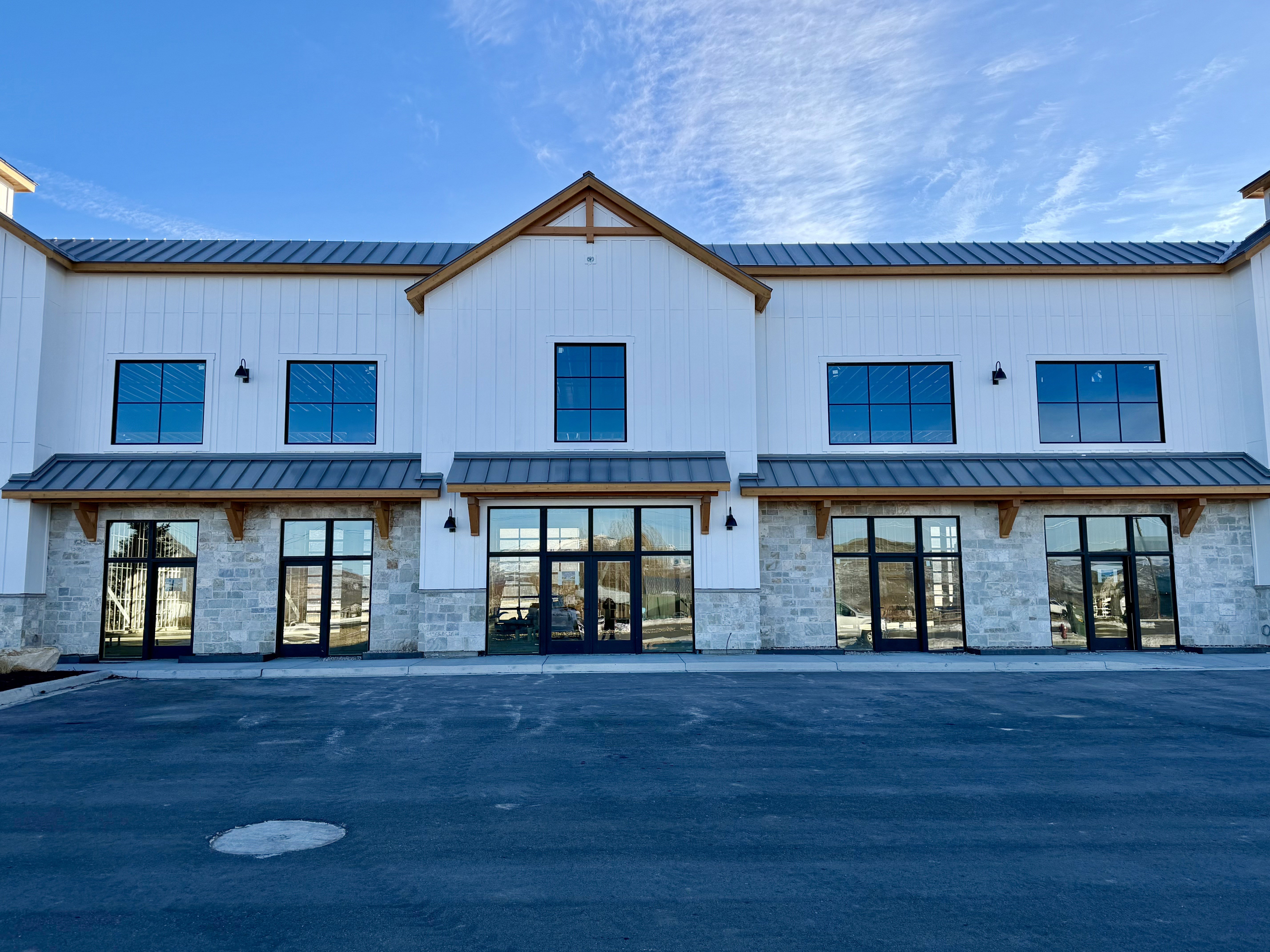Back of house with stone siding, a standing seam roof, and board and batten siding