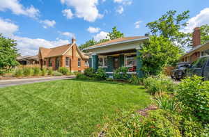 View of front facade featuring brick siding, a porch, and a front lawn