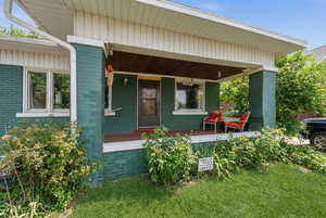 Doorway to property featuring covered porch and brick siding