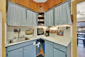 Kitchen with blue cabinets, light countertops, a ceiling fan, and open shelves