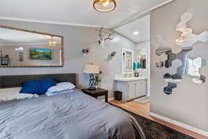 Bedroom with light wood-style flooring, vaulted ceiling, and ensuite bath