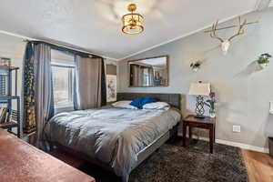Bedroom with lofted ceiling, ornamental molding, and wood finished floors