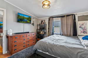 Bedroom with ornamental molding and wood finished floors