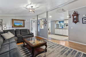 Living room featuring light wood-style floors, vaulted ceiling, ornamental molding, and cooling unit