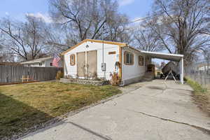 View of front facade with driveway, an attached carport, and entry steps