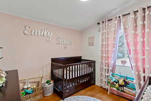 Bedroom featuring a nursery area and wood finished floors