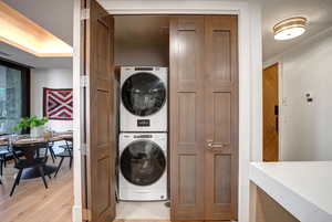 Laundry area featuring stacked washing machine and dryer and light wood-type flooring