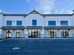 Back of house with stone siding, a standing seam roof, and board and batten siding