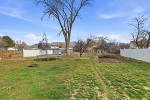 Fenced backyard featuring a trampoline and a mountain view