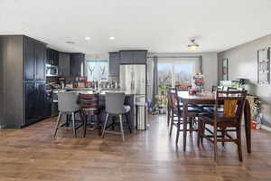 Kitchen featuring a kitchen breakfast bar, a center island with sink, dark wood-type flooring, stainless steel appliances, and recessed lighting