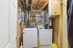 Laundry area featuring electric panel, washer and dryer, and cabinet space