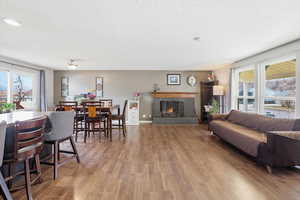 Living area with healthy amount of natural light, wood finished floors, a brick fireplace, and a textured ceiling