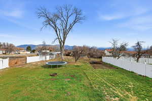 Fenced backyard with a trampoline, a residential view, and a mountain view