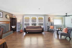 Sitting room featuring a high end fireplace, wood finished floors, a ceiling fan, a textured ceiling, and plenty of natural light