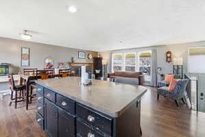 Kitchen featuring open floor plan, a center island, dark wood finished floors, and light countertops