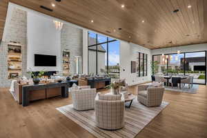 Living room featuring a large fireplace, a high wooden ceiling, light wood-style flooring, and hanging lights