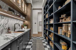 Bar area with dark cabinets, dark flooring, open shelves, glass insert cabinets, and tasteful backsplash