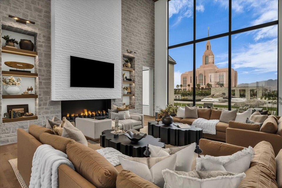 Living area with a fireplace, built in features, a high ceiling, wood finished floors, and expansive windows