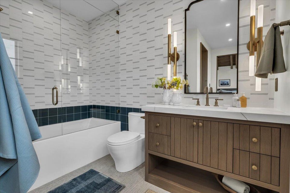Full bath featuring tile walls, shower / bath combination with glass door, and vanity