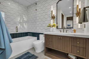 Full bath featuring tile walls, shower / bath combination with glass door, and vanity
