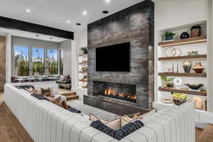 Sunken living room featuring built in features, wood finished floors, a large fireplace, and recessed lighting