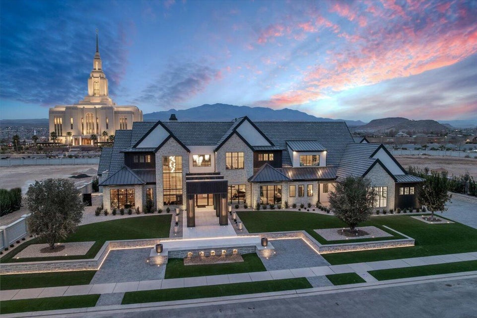 View of front facade with a standing seam roof, a lawn, a mountain view, stone siding, and a balcony
