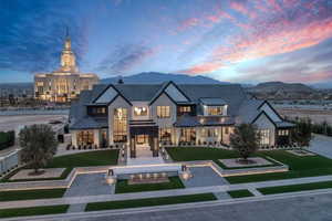 View of front facade with a standing seam roof, a lawn, a mountain view, stone siding, and a balcony