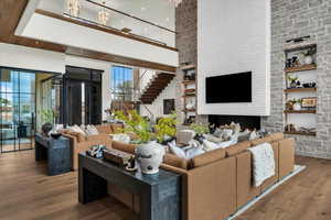 Living room with built in features, a high ceiling, wood finished floors, and a fireplace