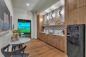 Indoor wet bar featuring open shelves, light countertops, light wood-style floors, modern cabinets, and wood finish cabinets