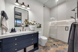 Full bathroom featuring a stall shower, vanity, and decorative backsplash