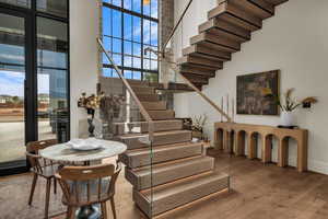 Stairs with a high ceiling and wood finished floors