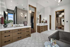 Full bathroom with two vanities, a chandelier, and a spacious closet