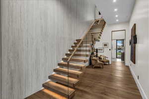 Stairway featuring wood finished floors, recessed lighting, and a high ceiling